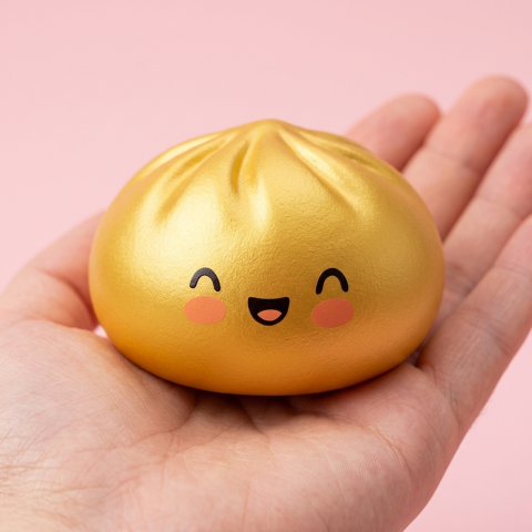 Dumpling Squishy Doré Lucky Goud in de hand gehouden, echte grootte